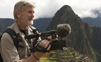 photograph of Boyd Matson holding a camera with mountain in the background